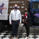 Two people standing near a vintage truck.